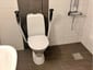 WC-installation i badrum med stödhandtag och golvbrunn